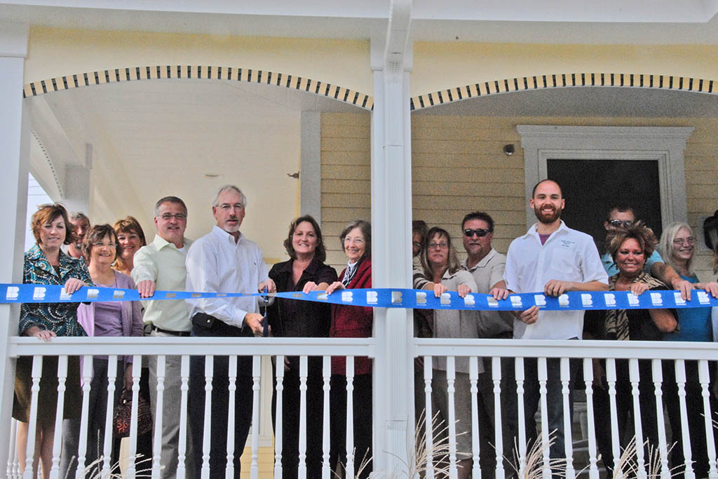 CFC employees hold blue ribbon at the Chamber of Commerce ribbon cutting event.
