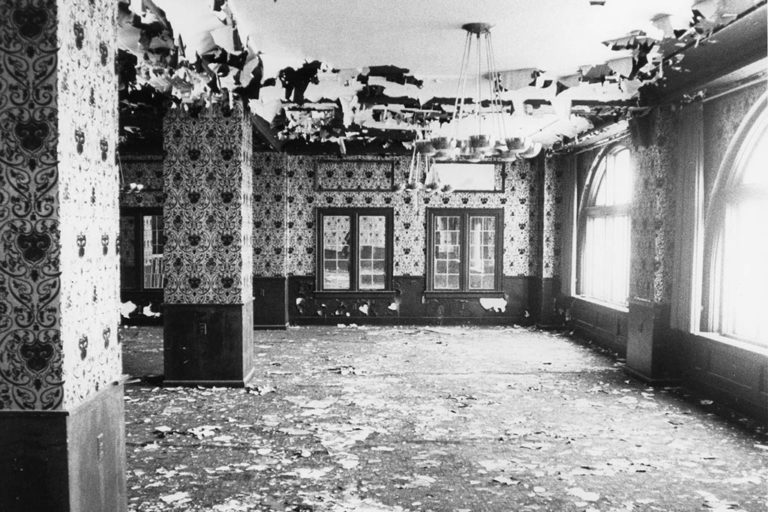 Graham Plaza's interior prior to the renovation – paint pealing off the ceiling, pigeon manure everywhere, striped wallpaper, bunched up carpet, and more.
