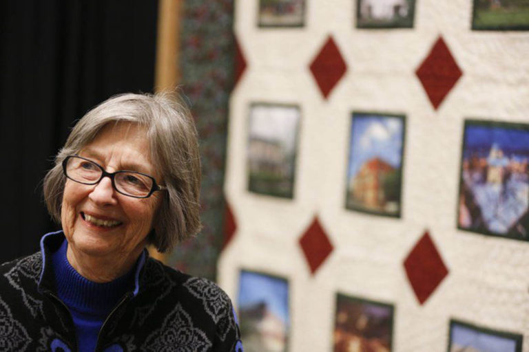 Gayle Cook, co-founder of Cook Medical, stands in front of CFC 30th anniversary quilt at the Indiana Heritage Quilt Show.