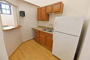 Cozy kitchenette with a sink, refrigerator, and serving window. Window overlooks the main room.